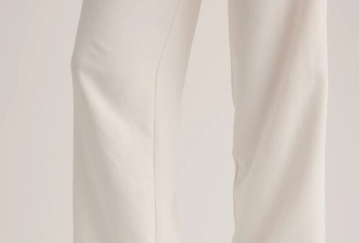 Person wearing white pants and beige slip-on clogs with a single button detail on the side.