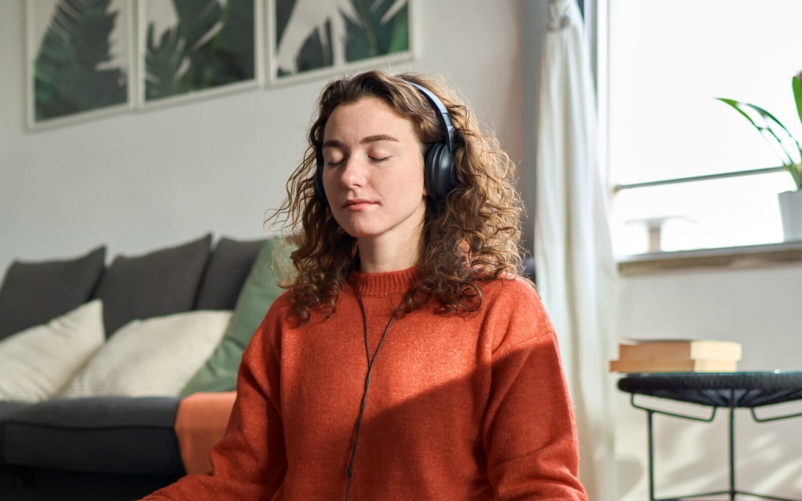 A woman meditating in lotus position with plants and flowers in the background