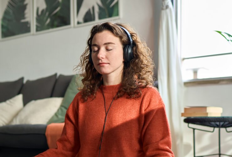 A woman meditating in lotus position with plants and flowers in the background