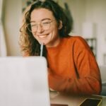 Young woman smiling while looking at laptop screen