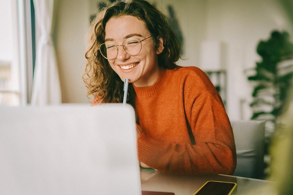 Young woman smiling while looking at laptop screen